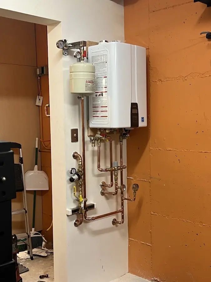 Plumbing technician inspecting water heater connections in Evergreen